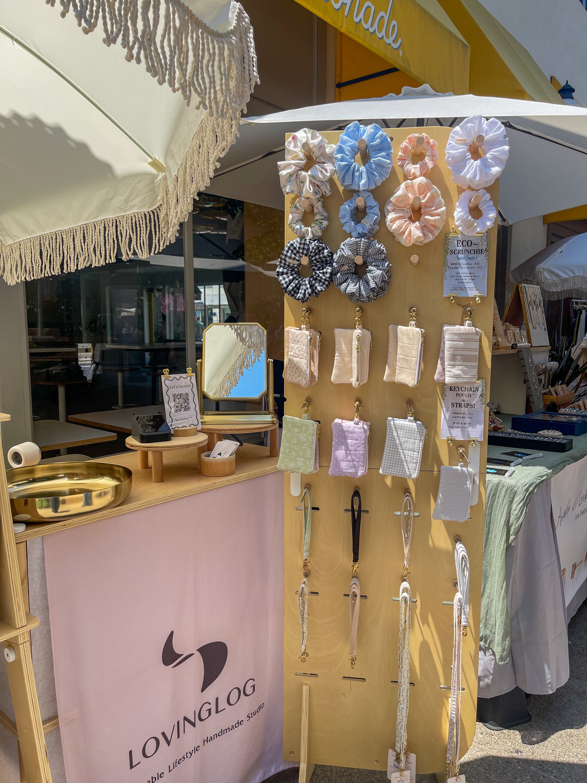 Display of handmade sustainable hair accessories at a market stall with 'LOVINGLOG' branding.