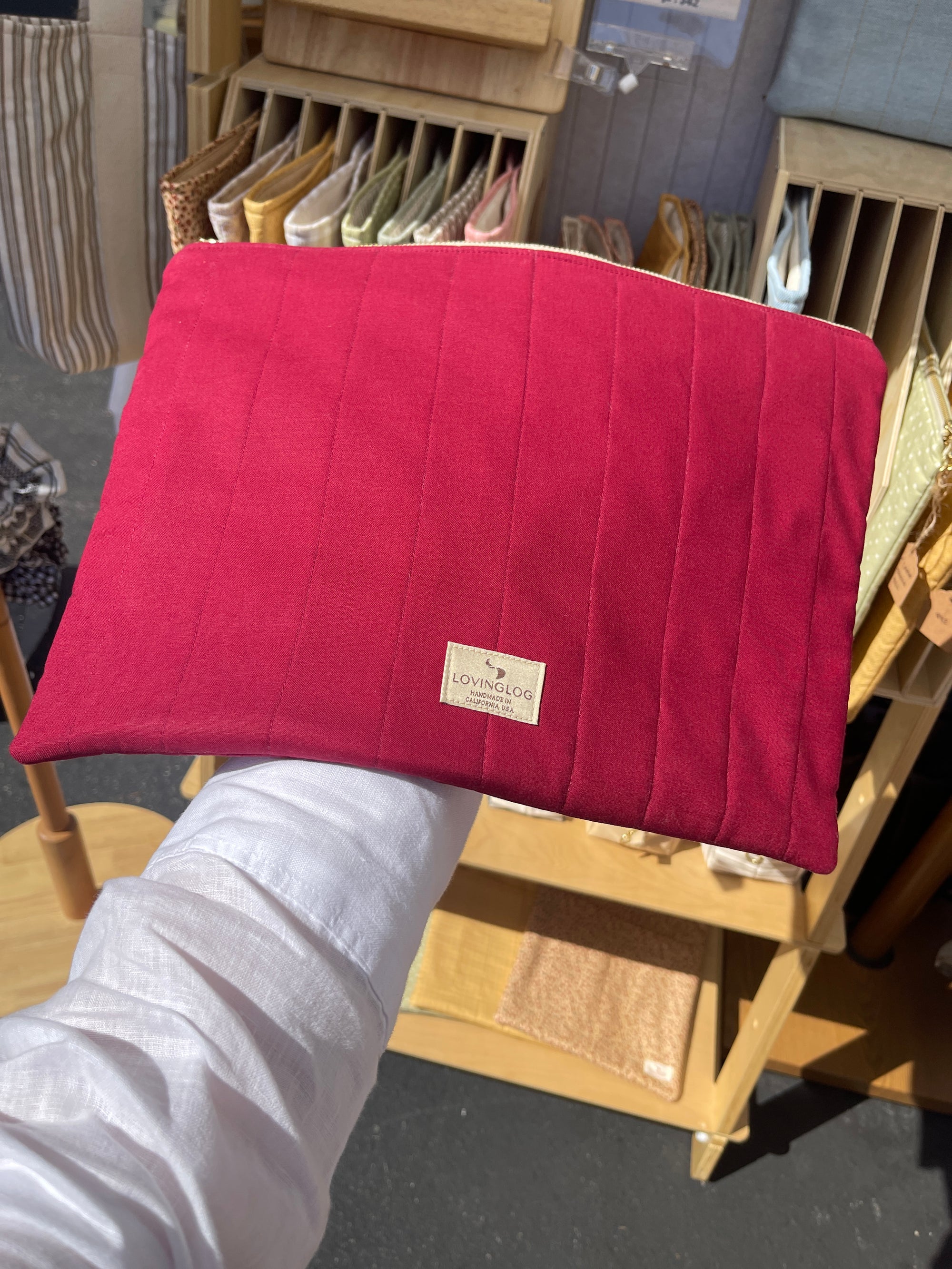 Handmade eco red cotton laptop sleeve held by a person with a blurred background