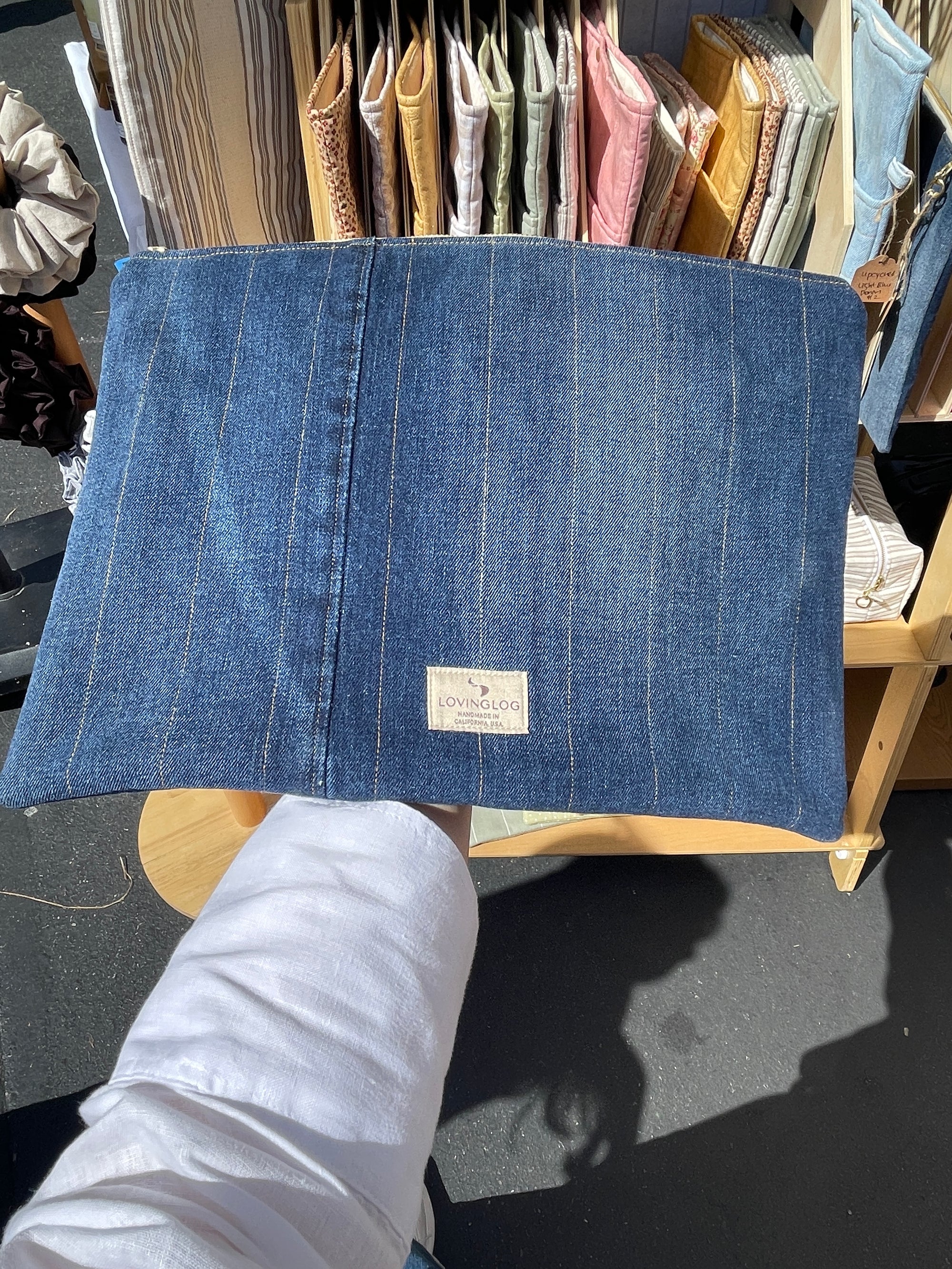 Handmade eco up-cycled blue denim laptop sleeve held by a person with a blurred background
