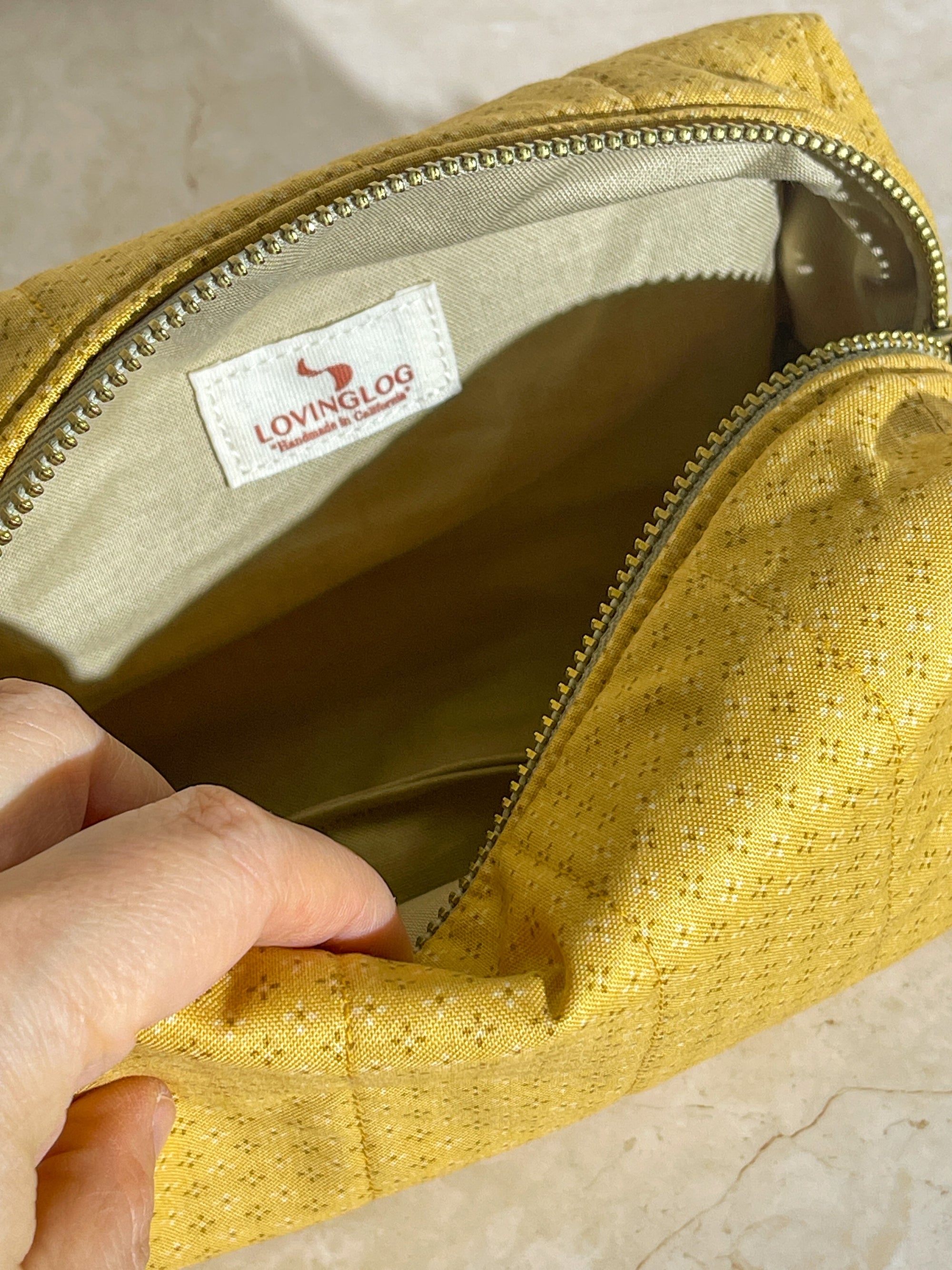 Interior view of the handmade sustainable quilted mustard yellow cotton boxy pouch, highlighting the gold zipper detail.