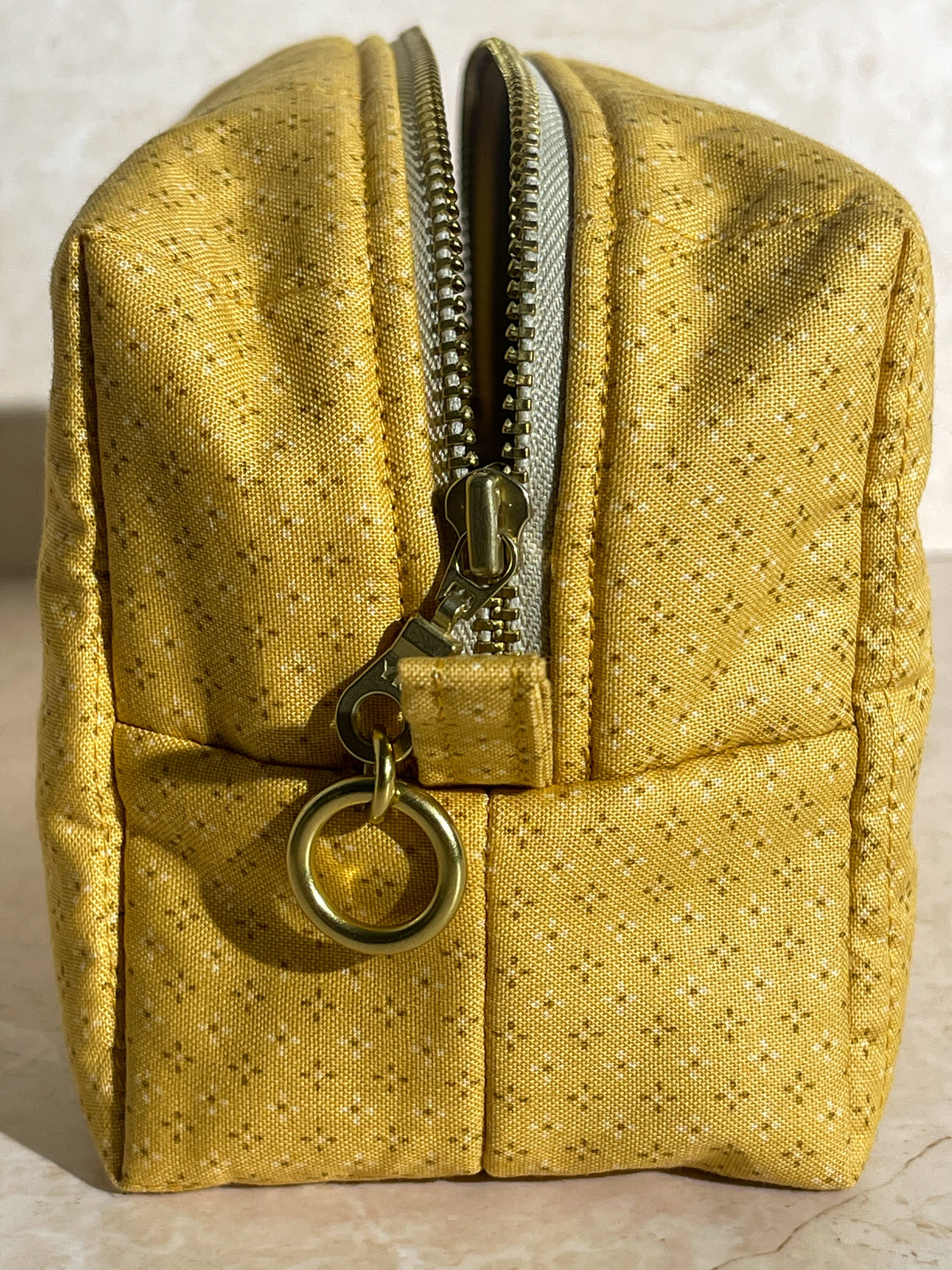 Side view of the handmade sustainable quilted mustard yellow cotton boxy pouch, highlighting the gold zipper detail.