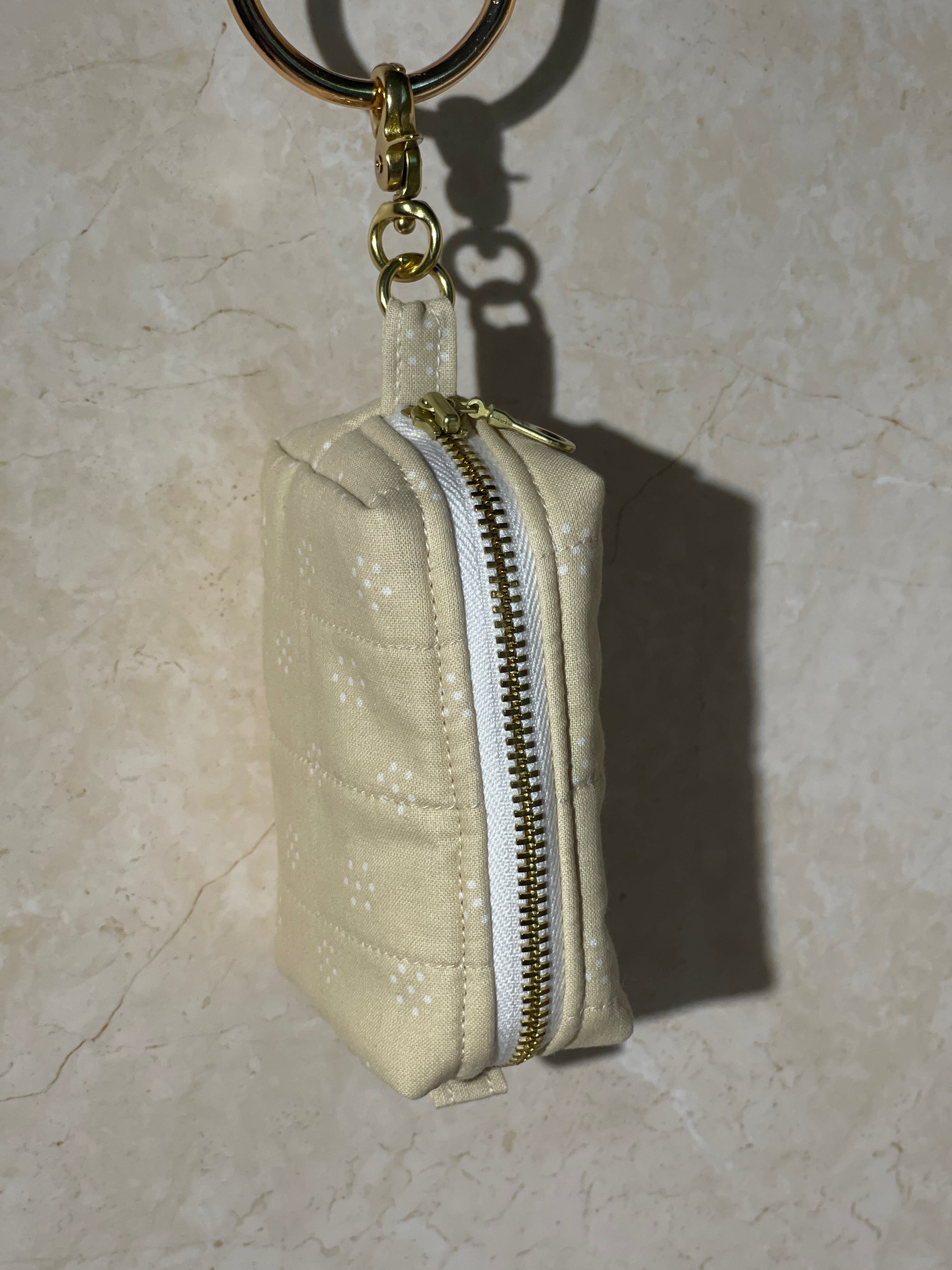 Lovinglog Handmade Sustainable beige cotton keychain pouch with a zipper on a light marble background