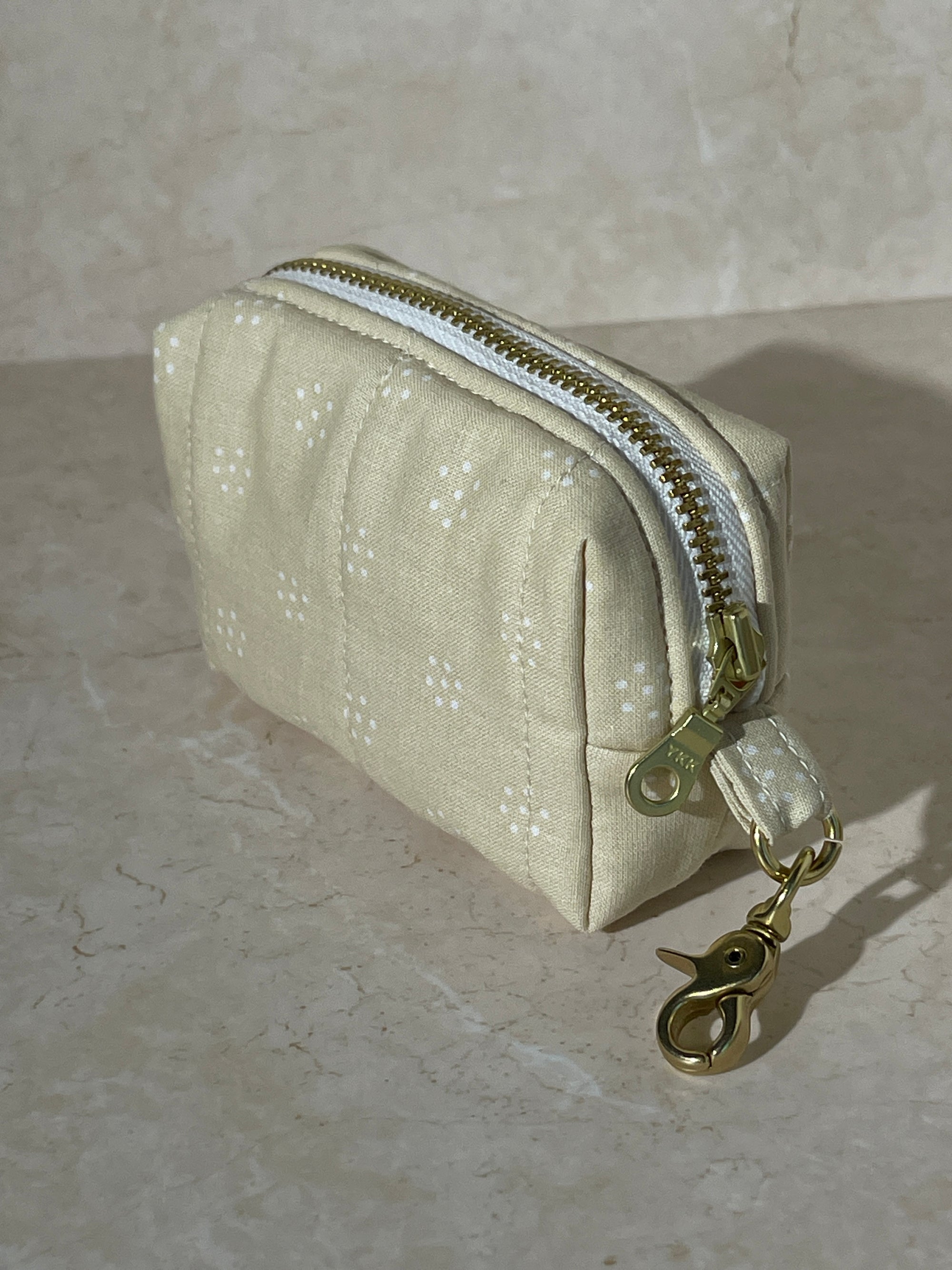 Lovinglog Handmade Sustainable beige cotton keychain pouch with a zipper on a light marble background