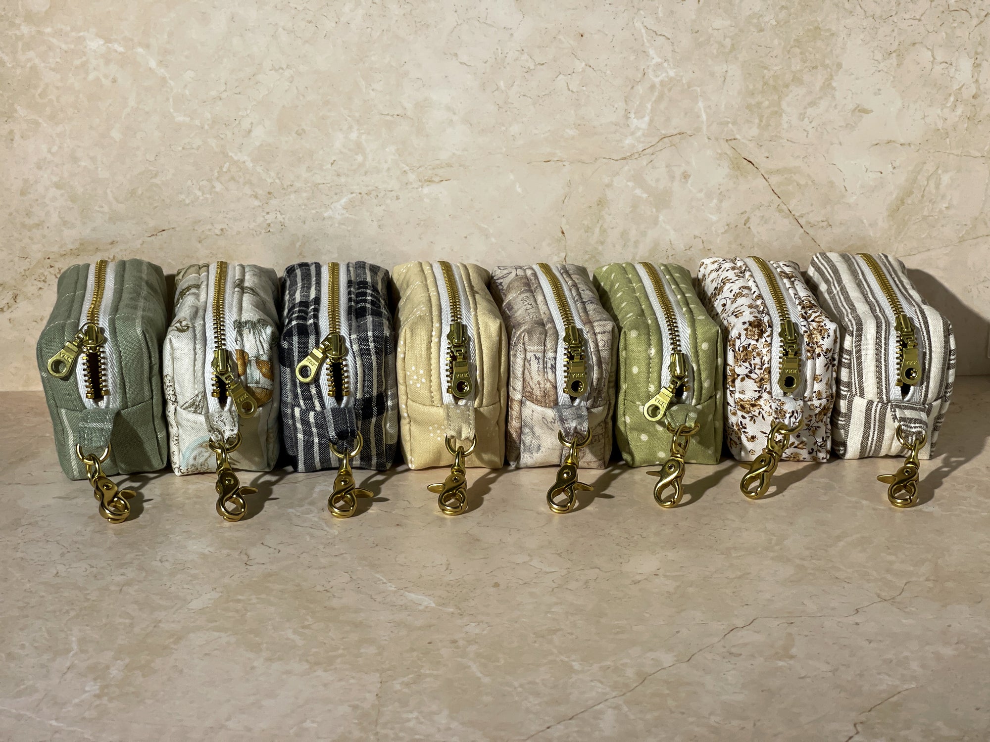 Row of small handmade fabric pouches with zippers on a beige surface