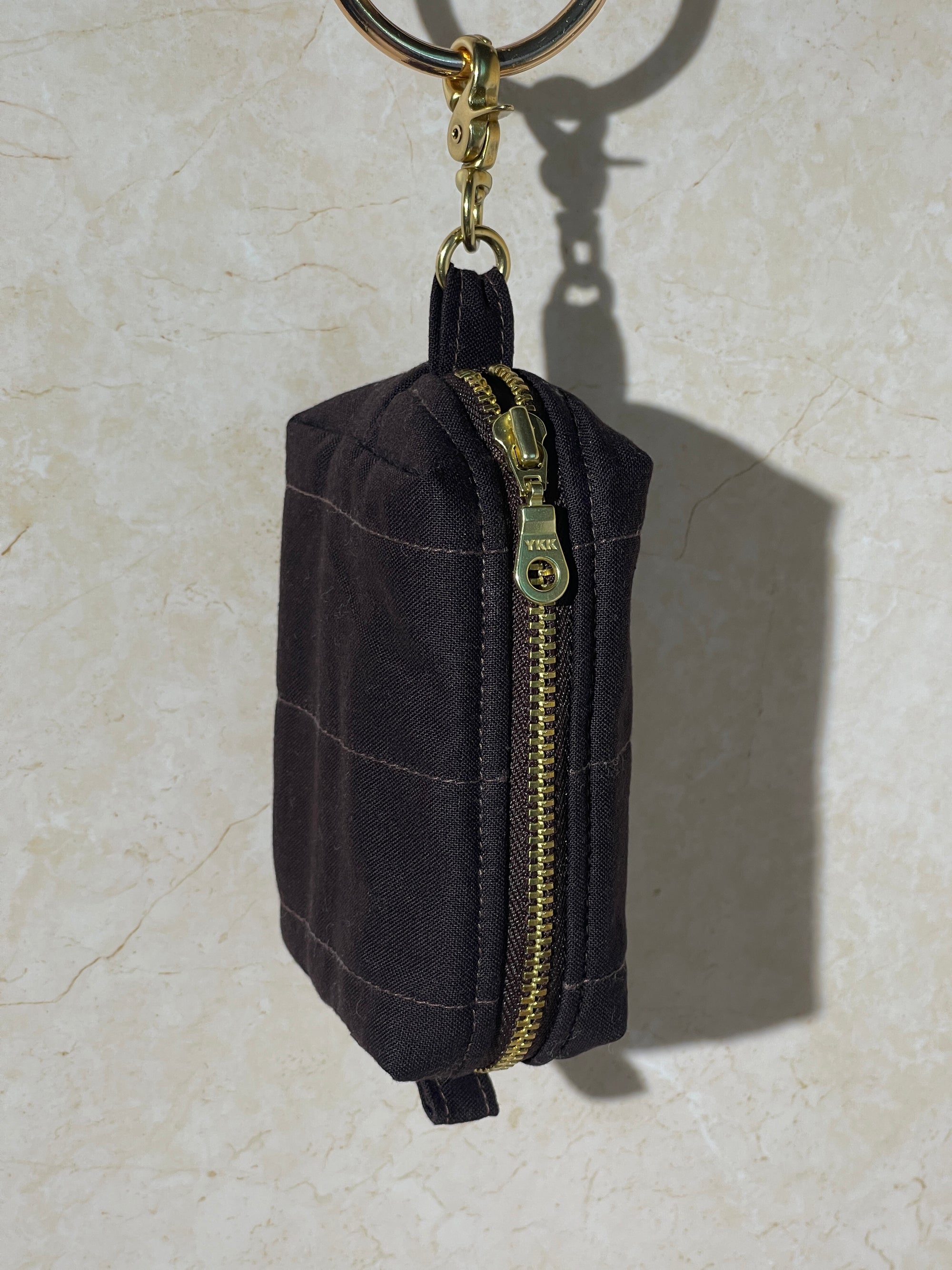 Lovinglog Handmade Sustainable espresso cotton keychain pouch with a zipper on a light marble background