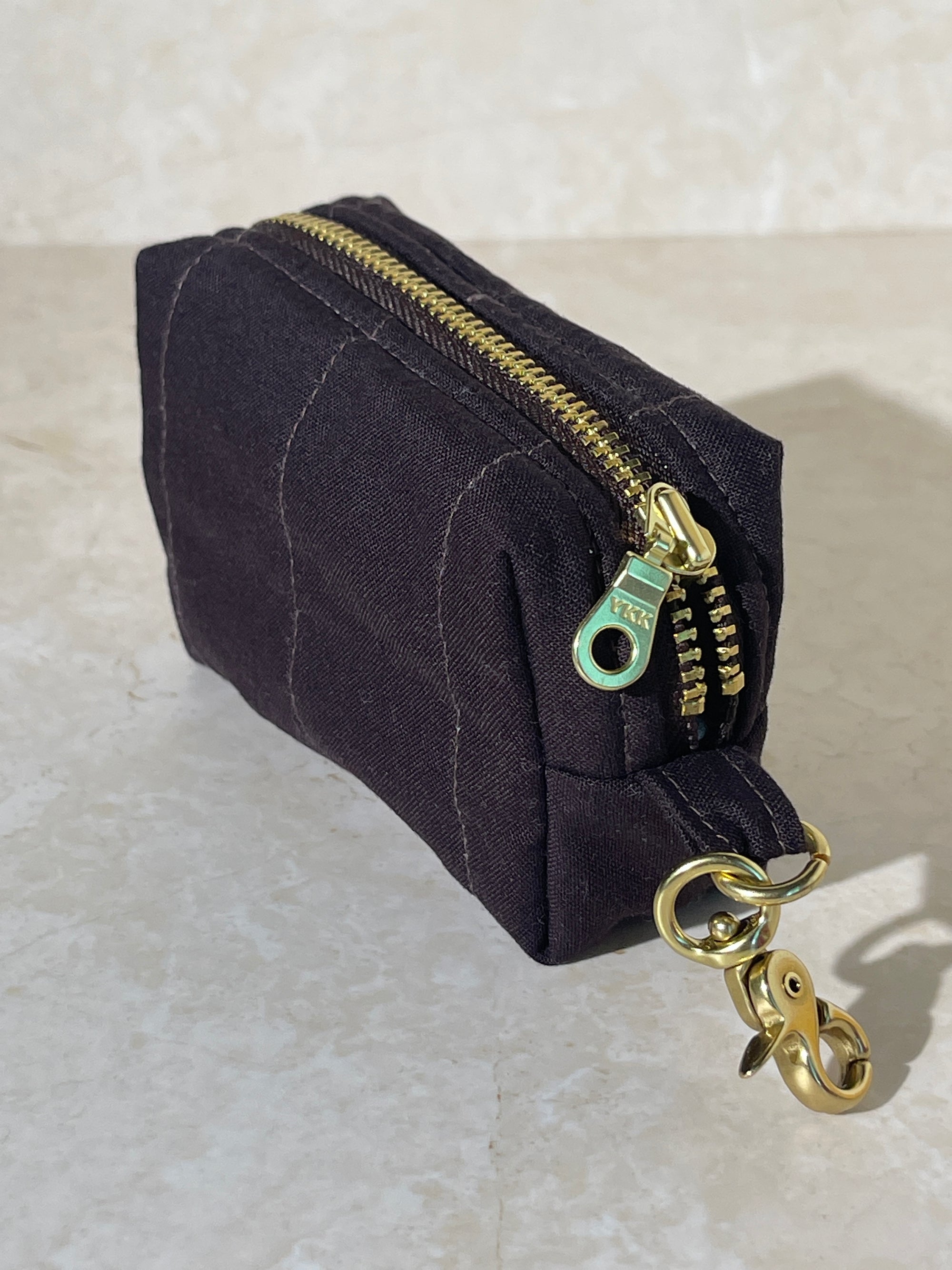 Lovinglog Handmade Sustainable espresso cotton keychain pouch with a zipper on a light marble background