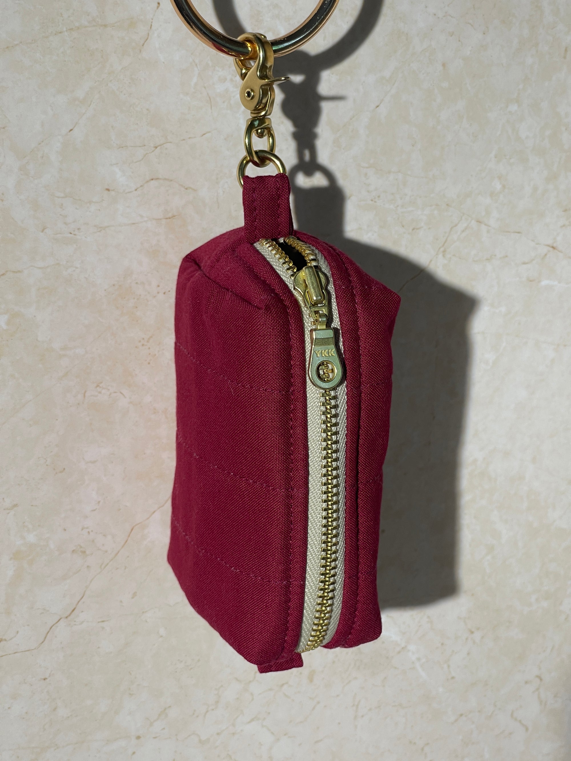 Lovinglog Handmade Sustainable red keychain pouch with a zipper on a light marble background