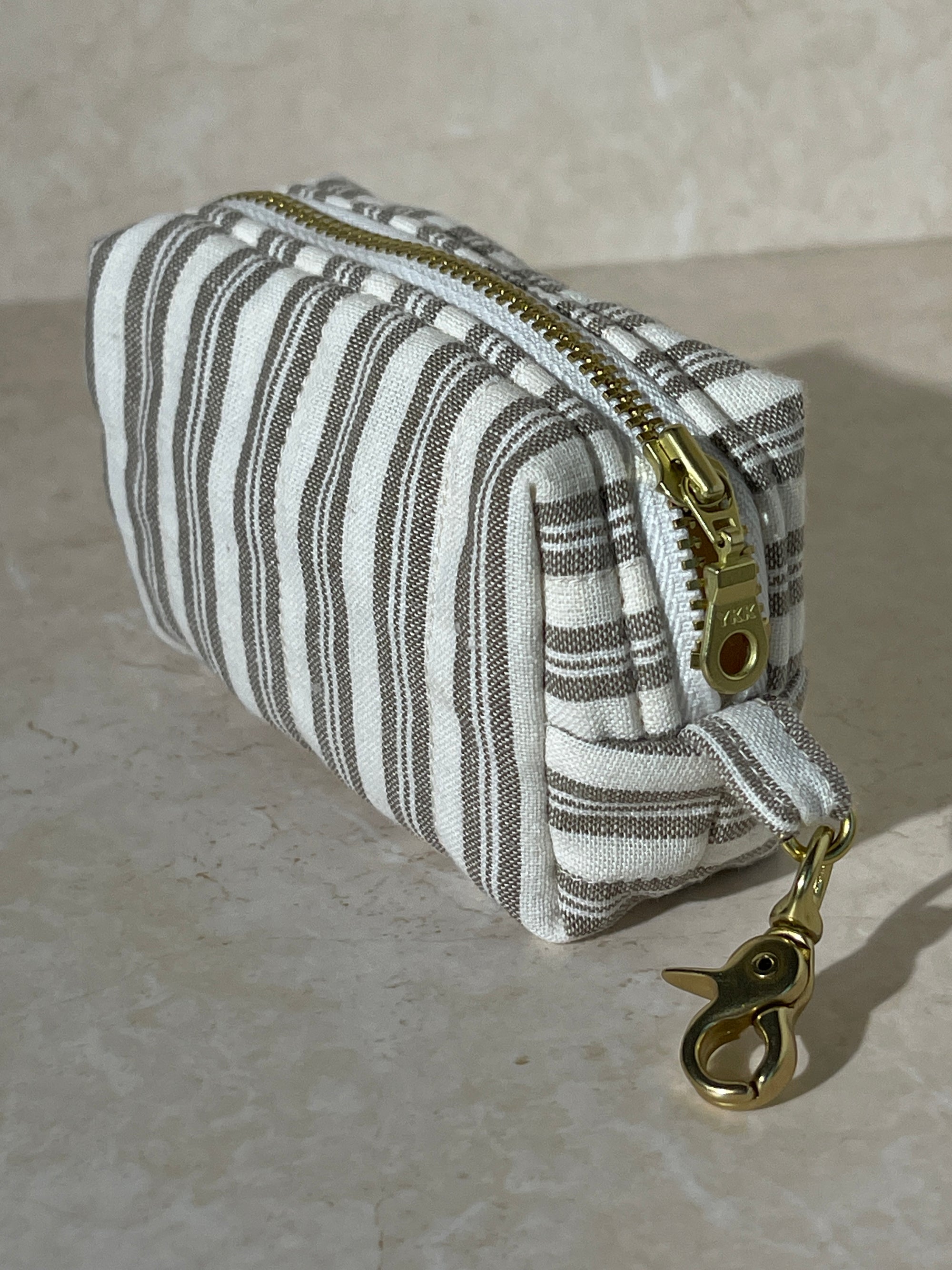 Lovinglog Handmade Sustainable striped cotton keychain pouch with a zipper on a light marble background