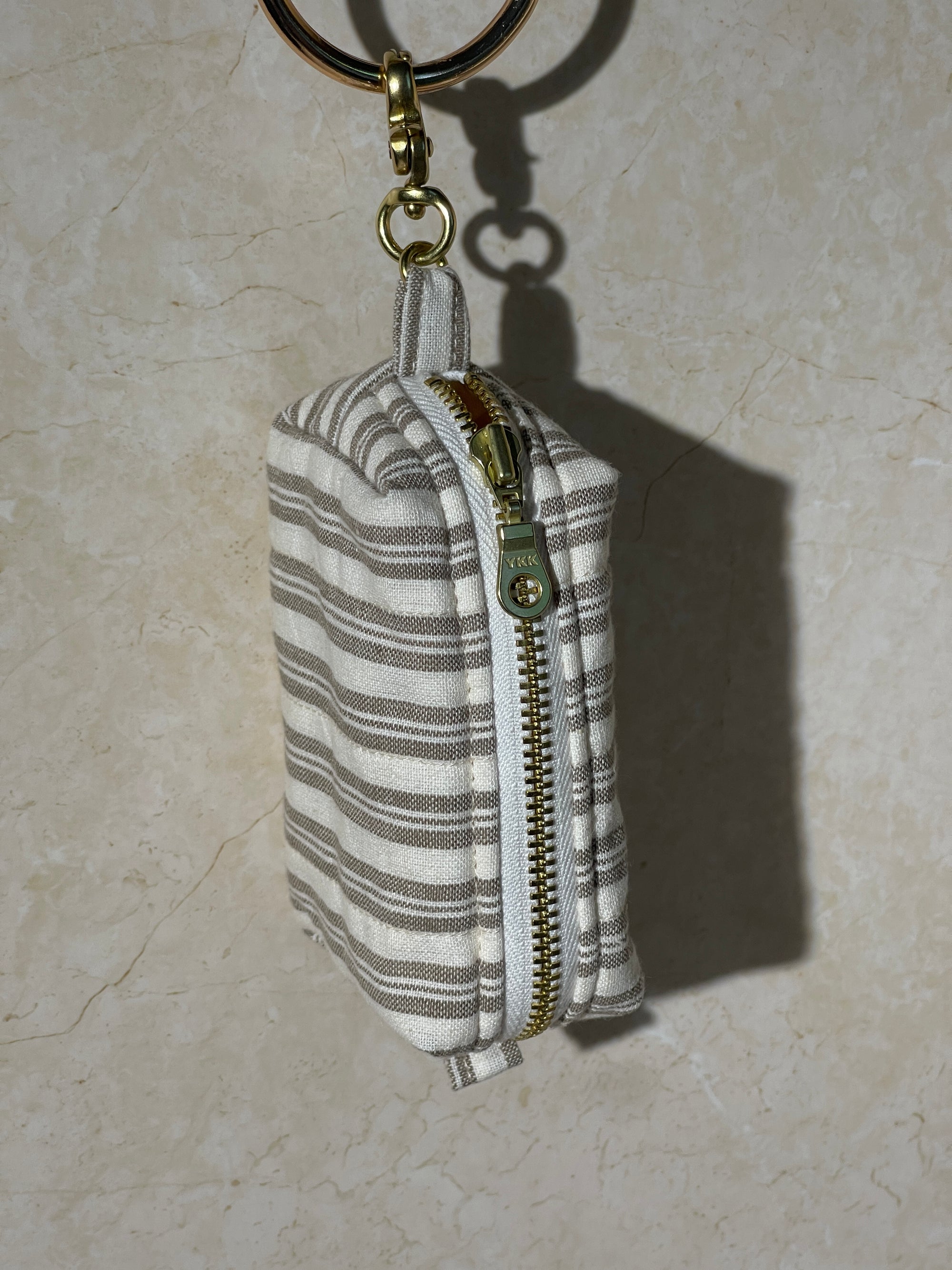Lovinglog Handmade Sustainable stripe cotton keychain pouch with a zipper on a light marble background