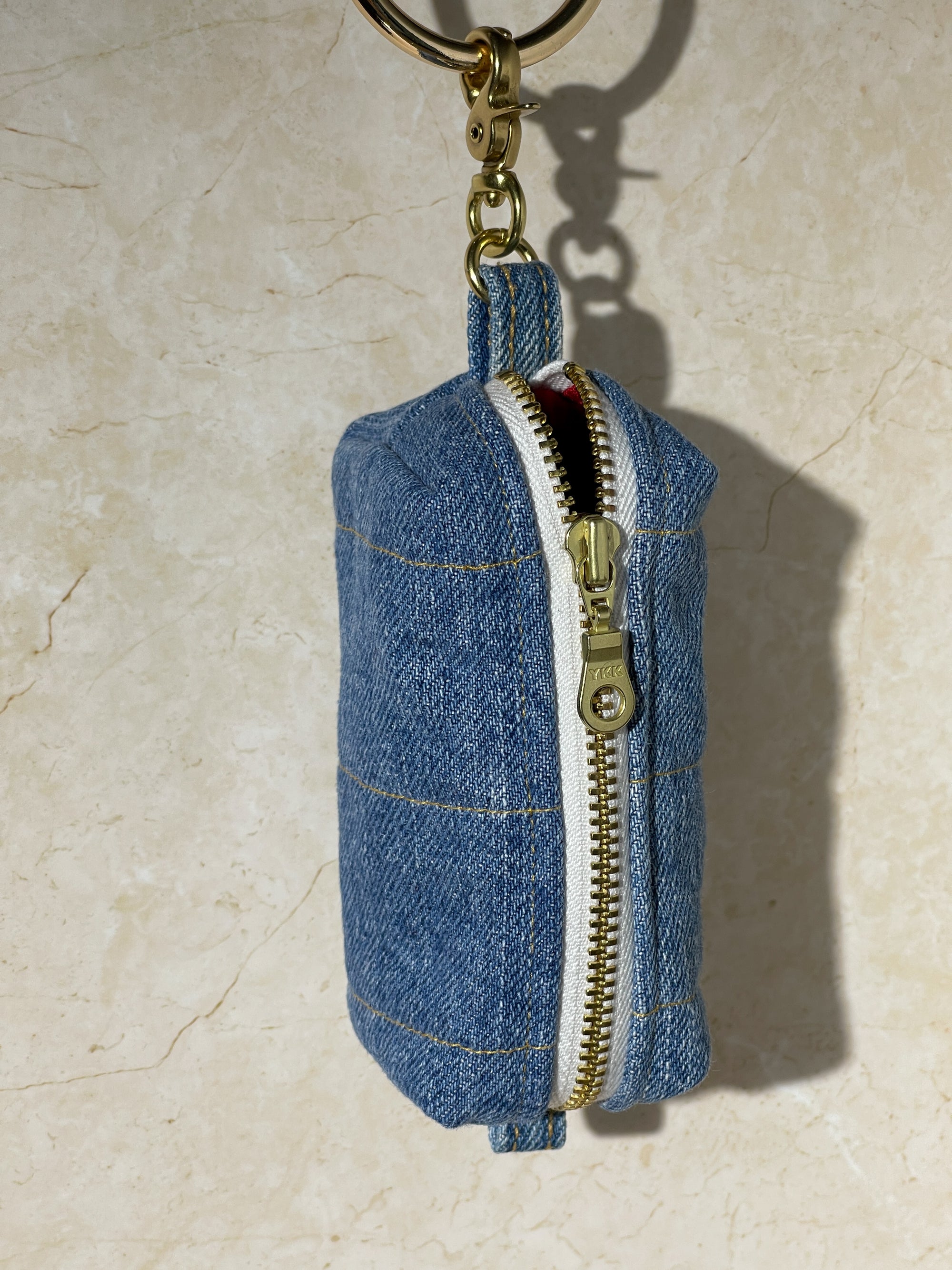 Denim upcycled keychain pouch with zipper on a beige background