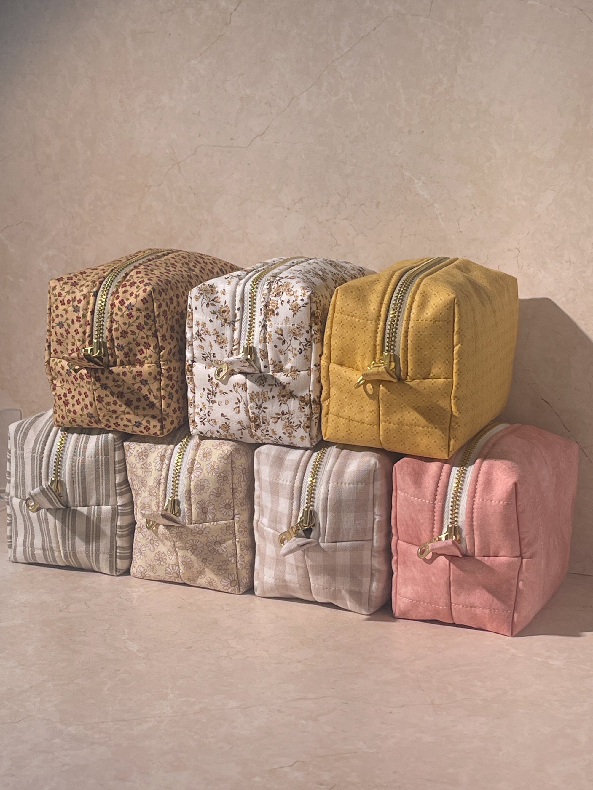 Set of colorful handmade sustainable makeup pouch bags with gold zippers on a neutral background