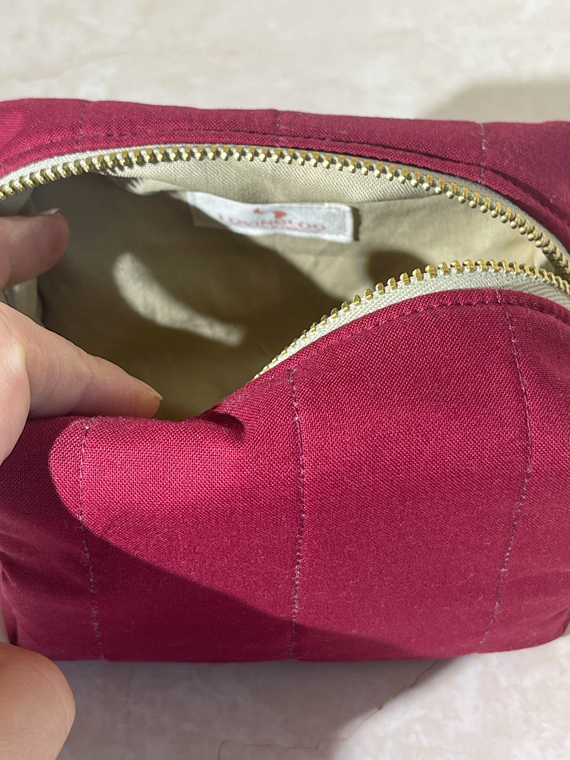 Close-up interior of a handmade sustainable makeup cotton pouch bag with a gold zipper, showing the brand label.