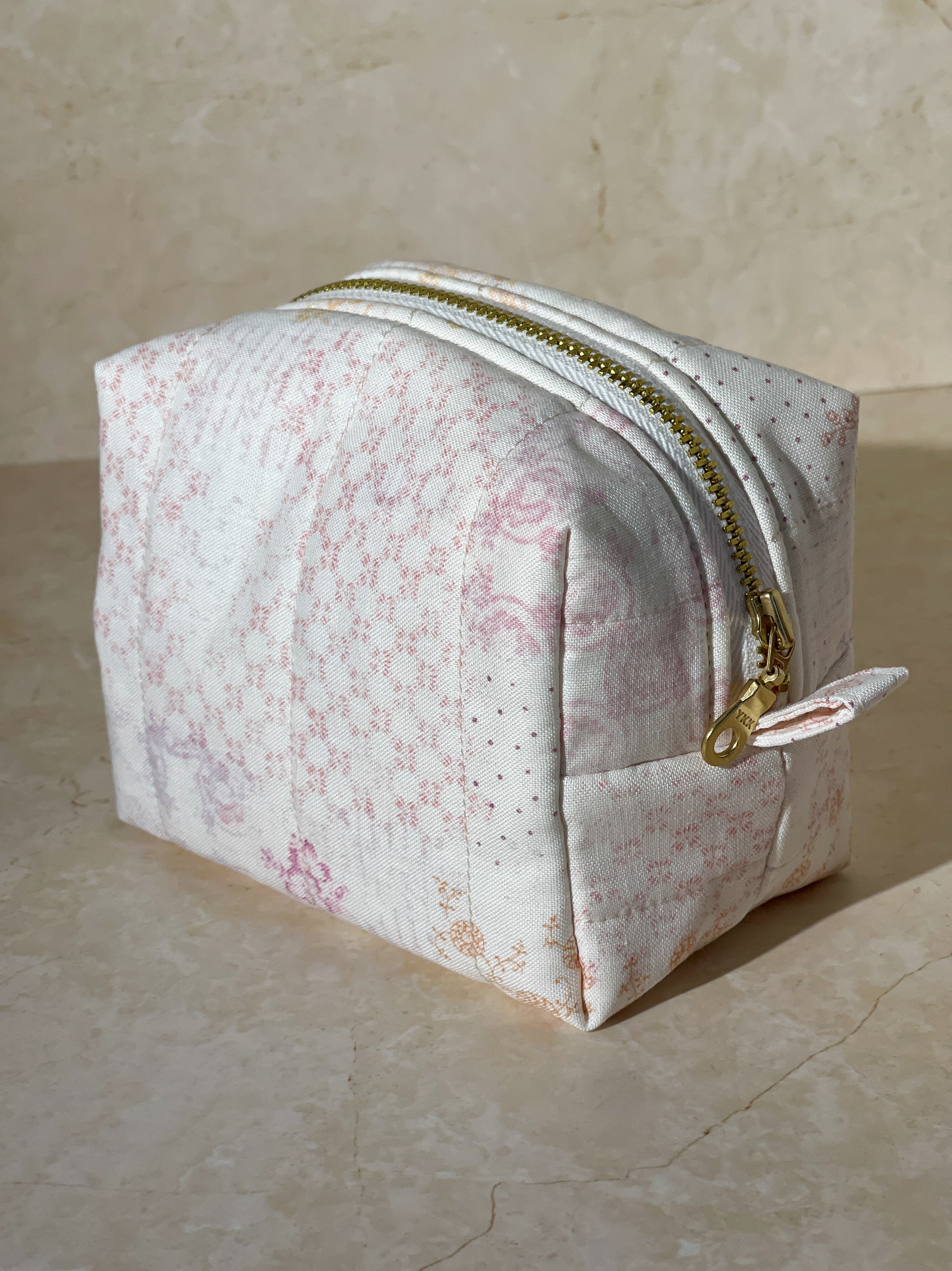 Dimensional view of the handmade sustainable quilted floral cotton boxy makeup pouch bag, highlighting the gold zipper detail.