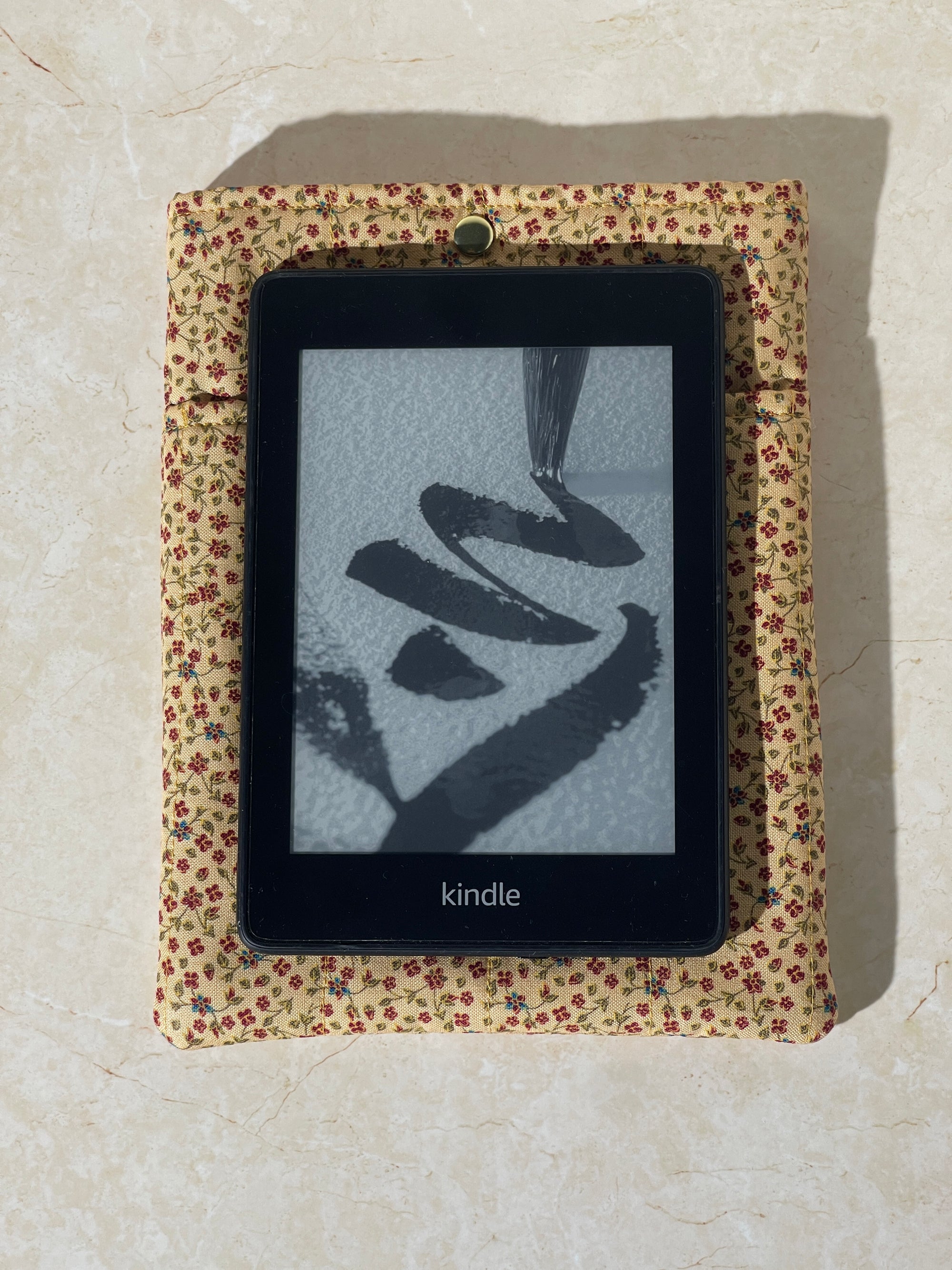 Kindle device on a Lovinglog Sustainable floral pattern cotton books, kindle sleeve on a beige surface