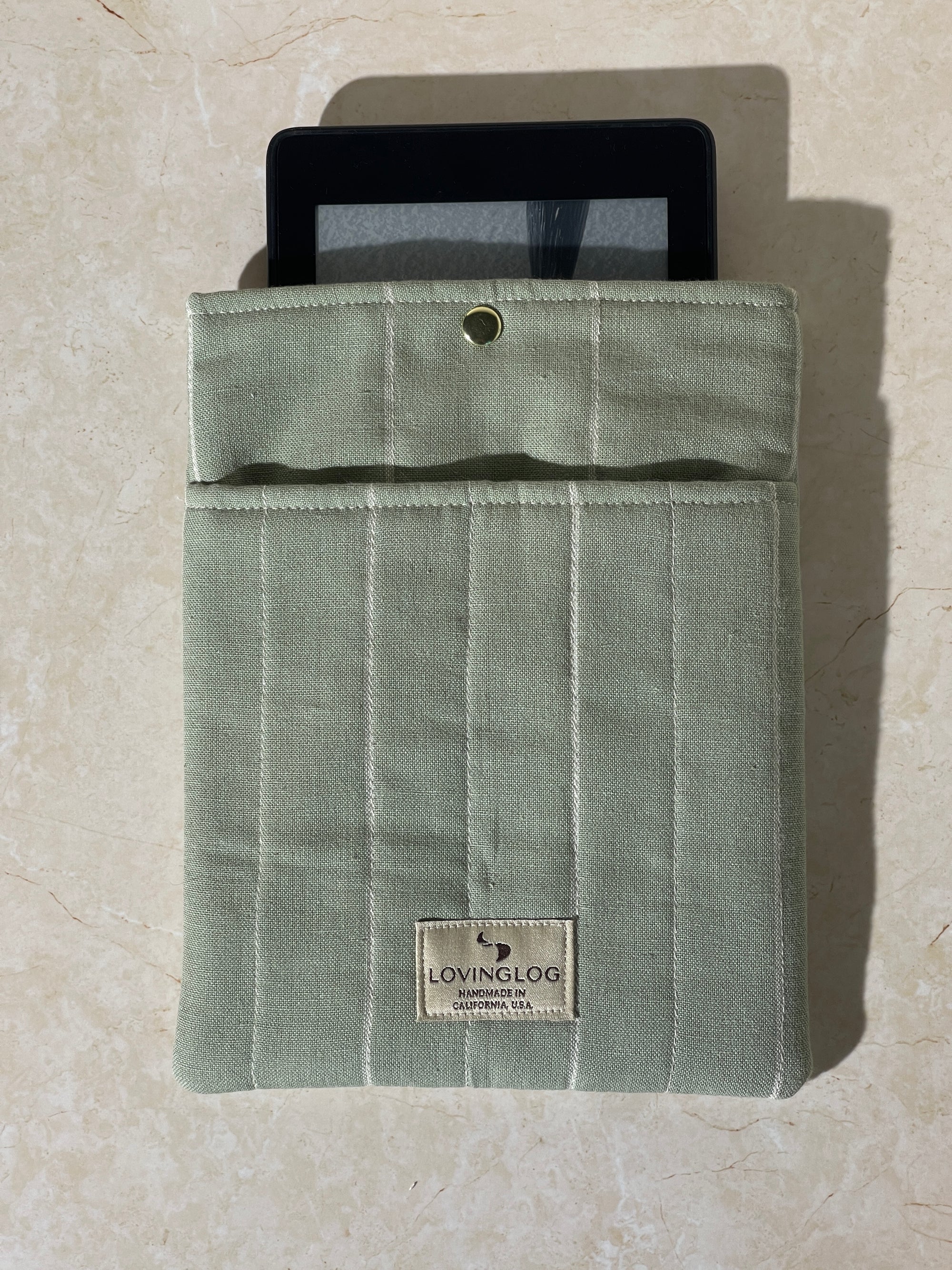 Kindle device on a Lovinglog Sustainable green cotton books, kindle sleeve on a beige surface