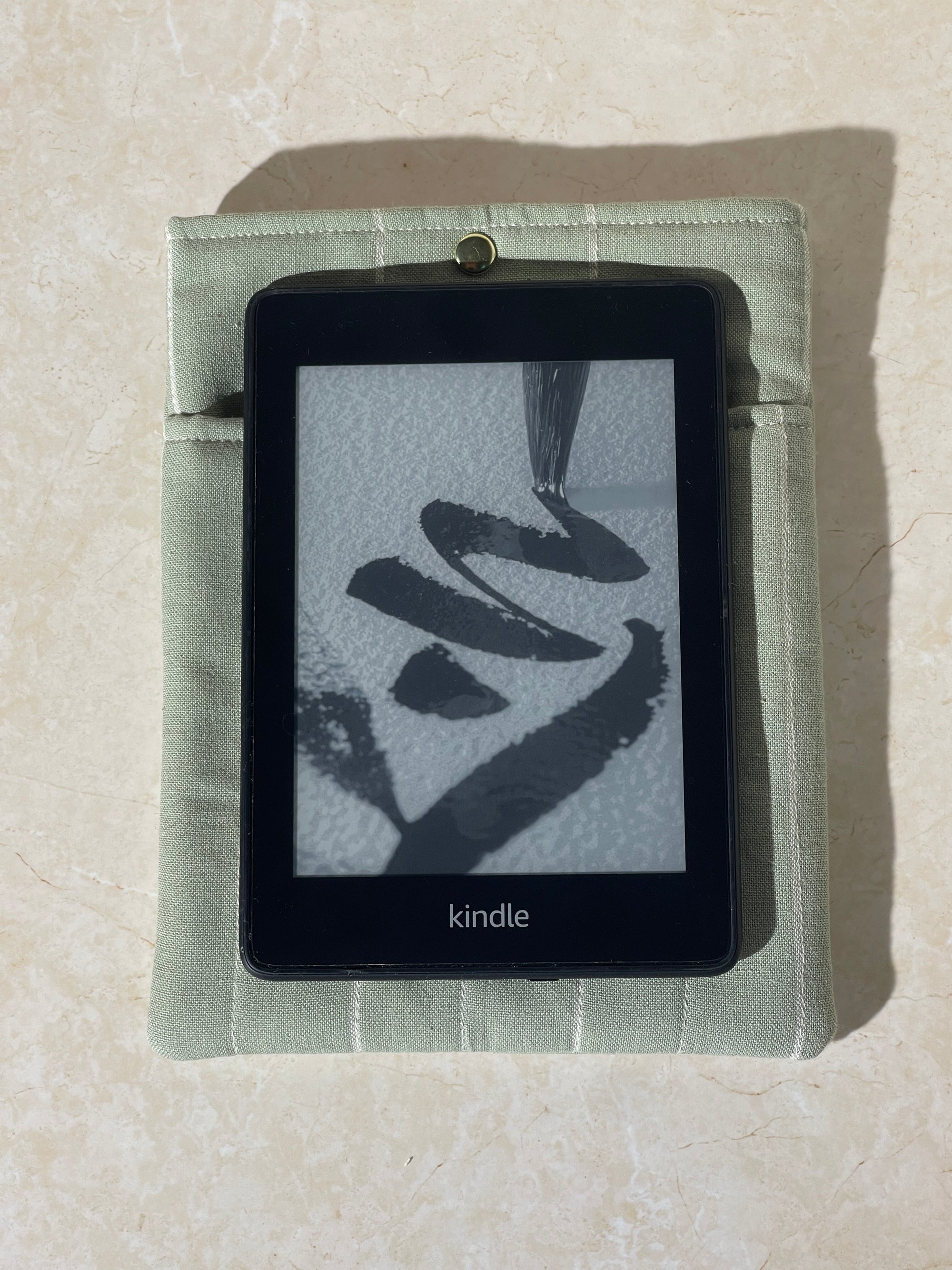 Kindle device on a Lovinglog Sustainable green cotton books, kindle sleeve on a beige surface