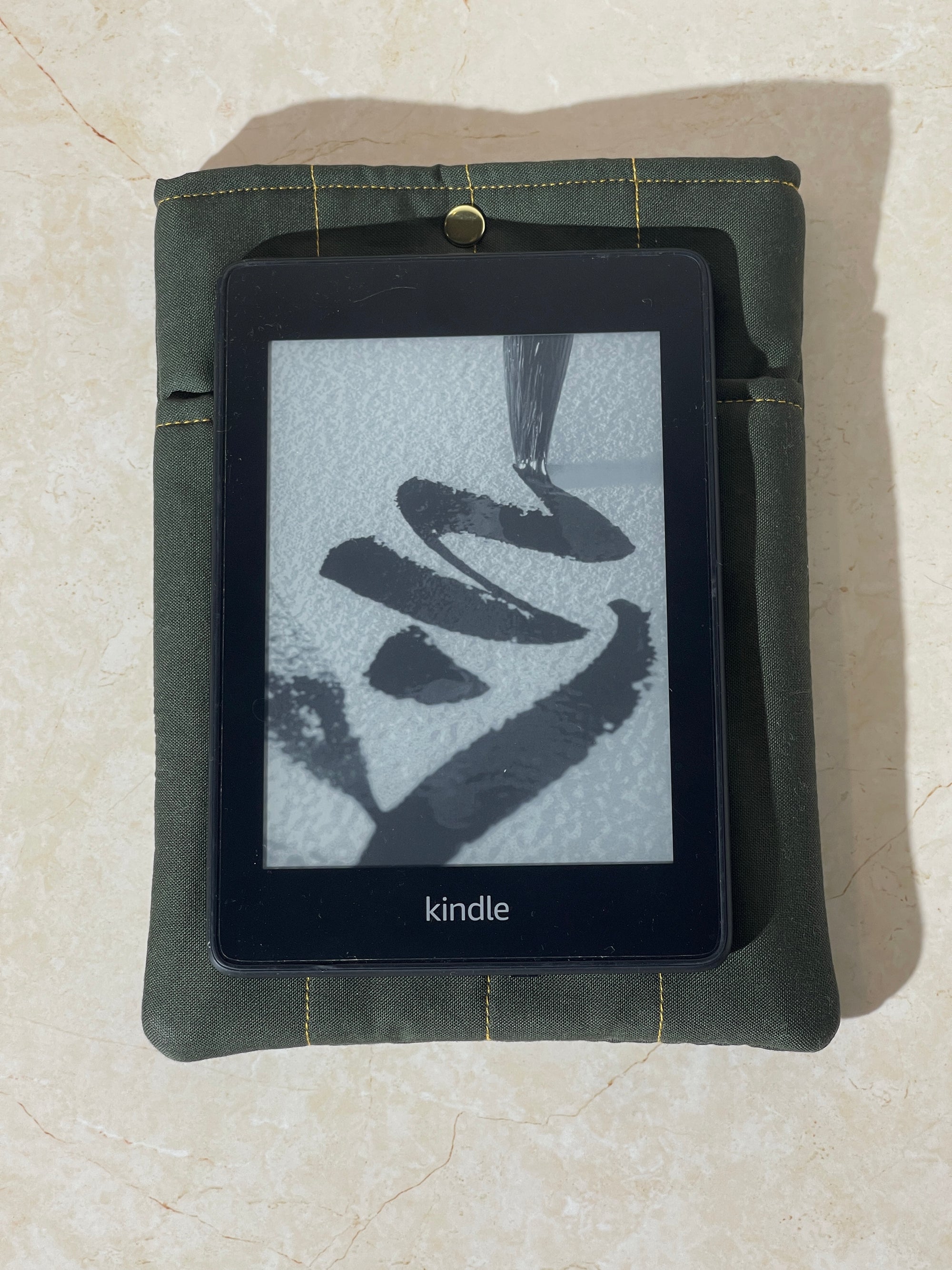 Kindle device on a Lovinglog Sustainable green cotton books, kindle sleeve on a beige surface