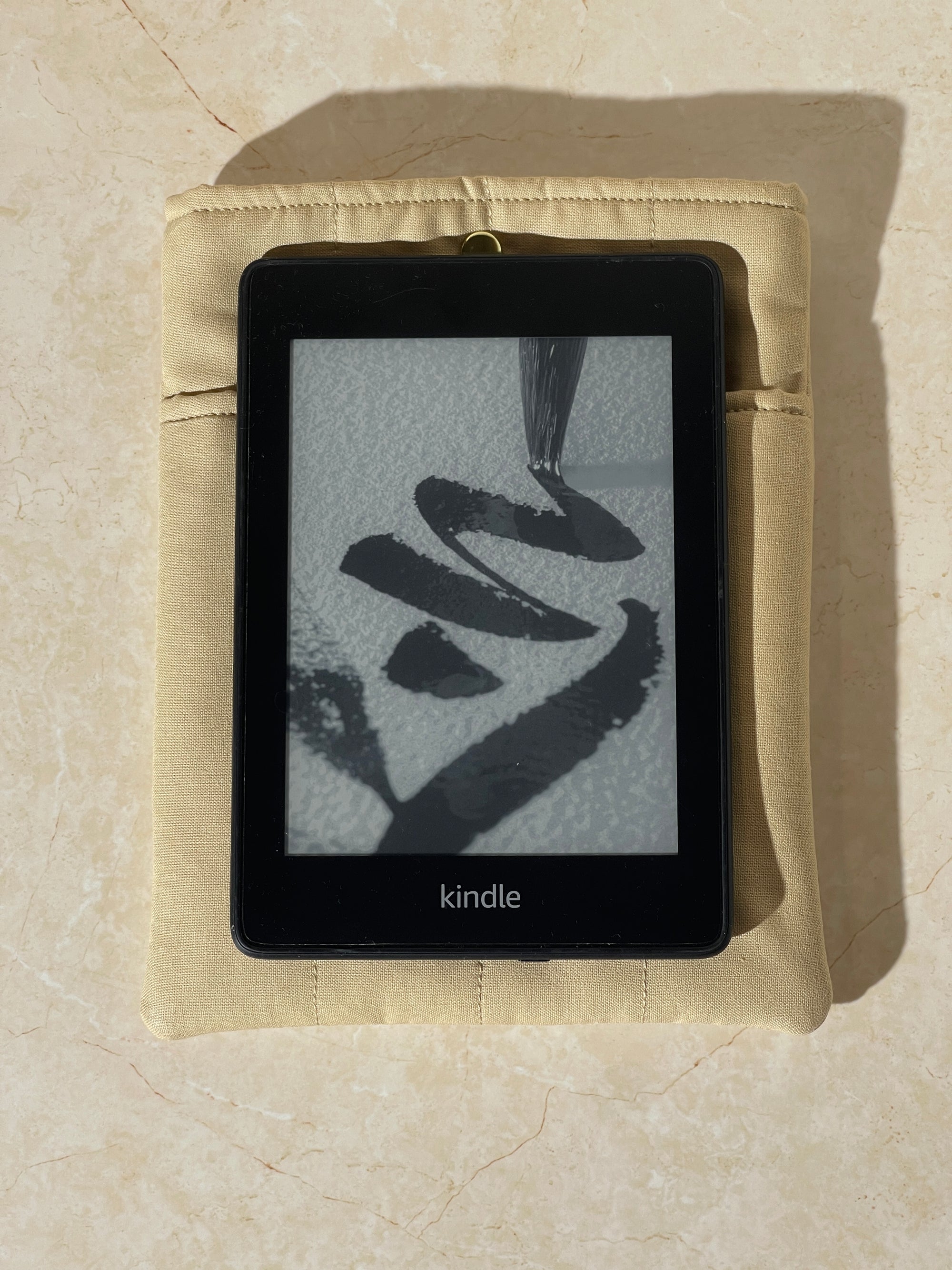 Kindle device on a Lovinglog Sustainable khaki cotton books, kindle sleeve on a beige surface