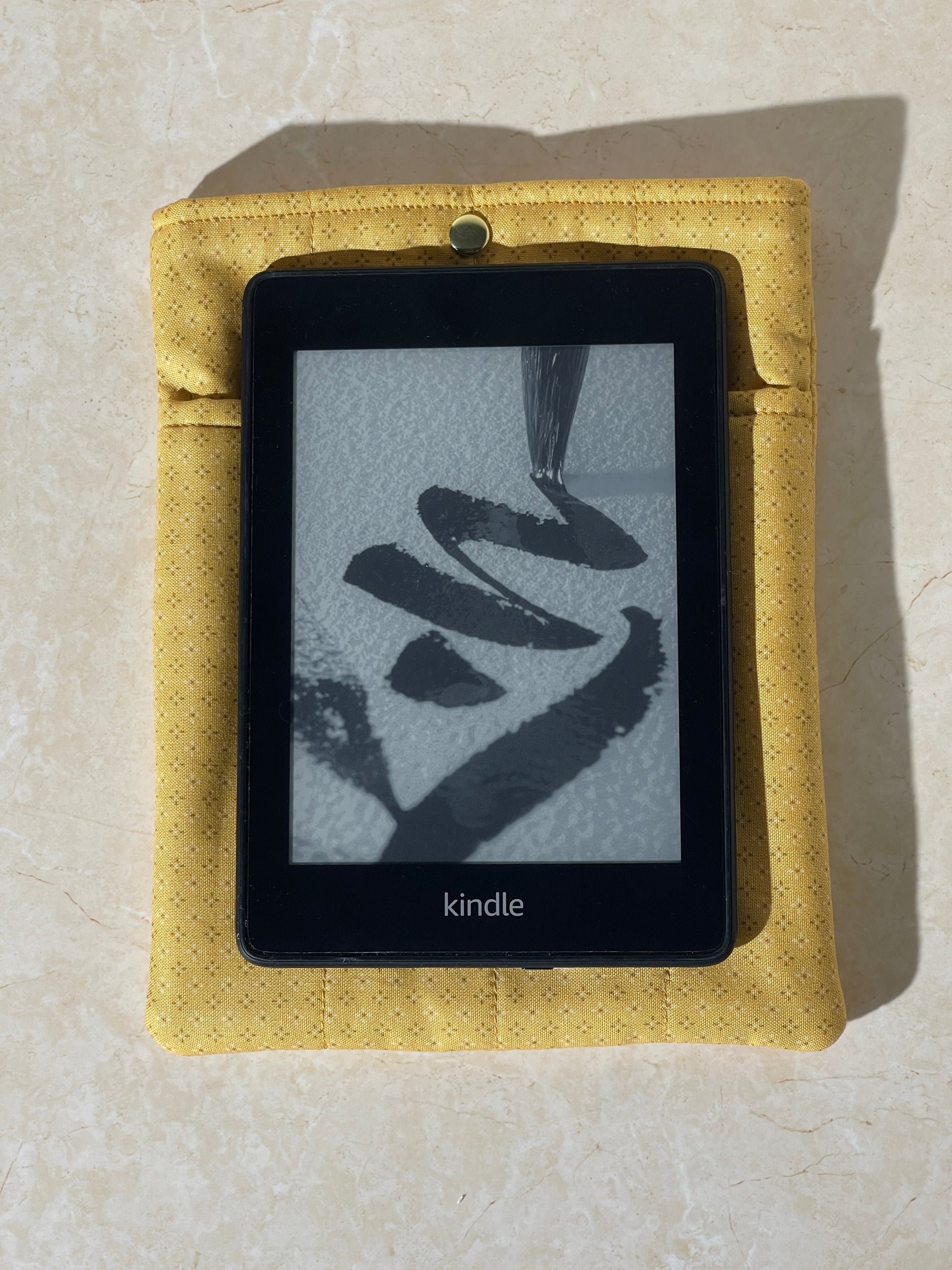 Kindle device on a Lovinglog Sustainable yellow cotton books, kindle sleeve on a beige surface
